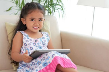 Sevimli gülümseyen kız koltukta oturan tablet bilgisayar ile