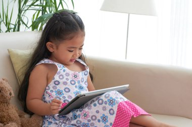 Küçük kız dijital tablet üzerinde oyun oynama