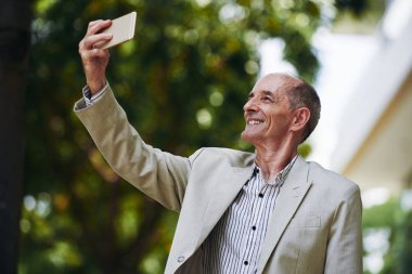 Gülümseyen ve selfie için poz mutlu yaşlı işadamı