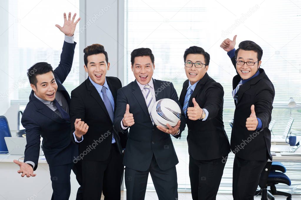 Cheerful white collar workers posing for photography and holding ball 