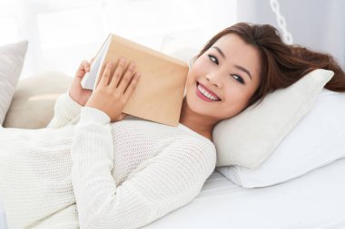 Güzel çekici genç kadın bir kitapla yatakta yalan