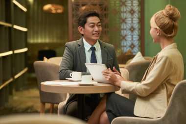 Vietnamca girişimci planları kafede toplantı sırasında iş ortağı ile tartışıyor