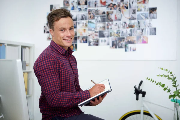 Joven Hombre Negocios Sonriente Escribiendo Planes Bloc Notas —  Fotos de Stock