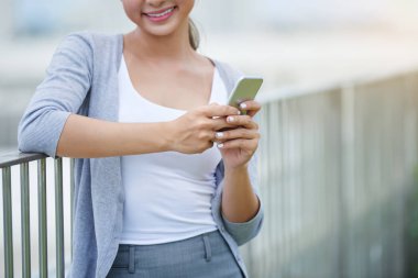 Smartphone açık havada duran ile Vietnam iş kadını gülümseyen bir kırpılmış görüntü