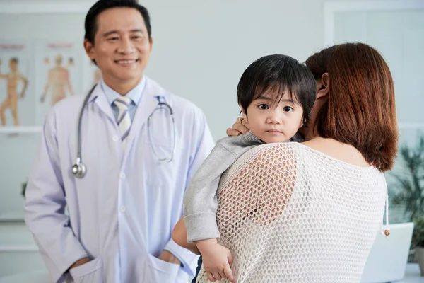 女性医師に話をしながら幼い息子を抱きしめるの背面図 — ストック写真