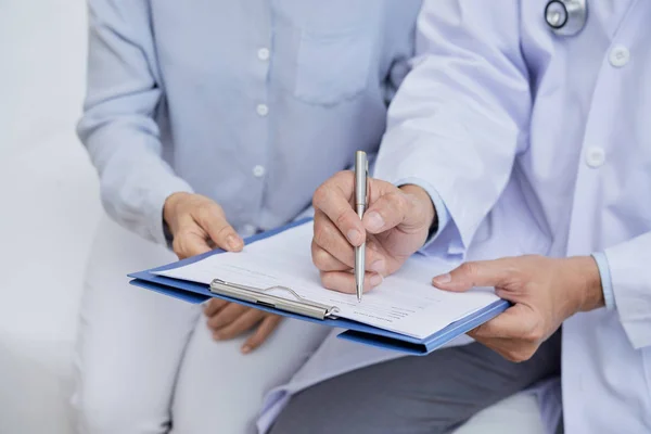 Medico Che Tiene Appunti Mano Mentre Aiuta Paziente Anziano Compilare — Foto Stock