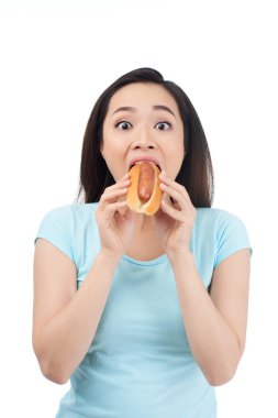 Asyalı Genç kadın lezzetli sosisli sandviç yiyip bitiren heyecanlı