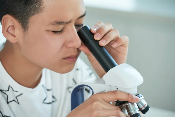 好奇的十几岁的男孩在显微镜下研究化学物质 — 图库照片