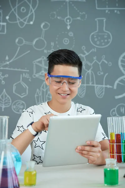 在化学课堂上佩戴安全护目镜的青少年学生微笑着浏览数码片 — 图库照片