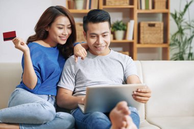 Güzel Asyalı kadın ve Internet kredi kartı ile alışveriş ve dizüstü bilgisayar ile Divan tüyler ürpertici adam