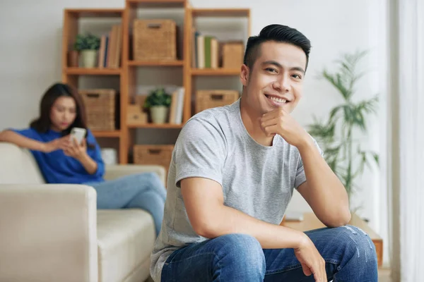 Veselý Asijské Muž Sedí Při Pohledu Fotoaparát Ženou Pomocí Smartphone — Stock fotografie