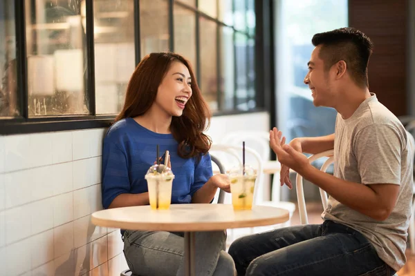 アジアの若いカップルがカフェを持つ低温飲料カップとおしゃべりしながら嬉しそうに笑って — ストック写真