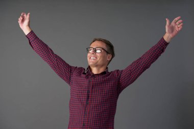 Mutlu heyecanlı genç adam kollarını yükselen gözlük