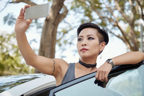 かなりアジアの女性の携帯電話に Selfie を取って車で — ストック写真