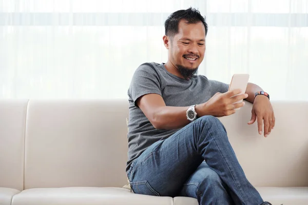 Tagalogština Muž Sedí Pohovce Čte Jeho Telefonu — Stock fotografie