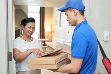 Belgeyi imzalamak için kadın kıdemli tablet veren kurye