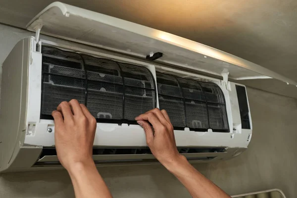 Hands of handyman repairing broken air conditioner, cropped image