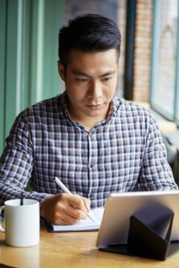 Ciddi Asya adam not defterinde tabletten bazı bilgi yazma