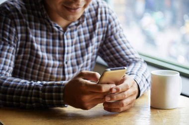 Genç adam masada Kupası ile tarama cep telefonu 