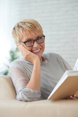 Bir kitapla oldukça yaşlı gülümseyen kadın