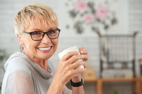 コーヒーのマグカップと美しい笑顔のシニア女性 — ストック写真
