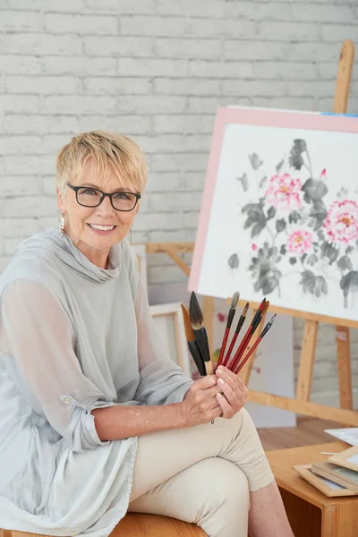 Feliz Anciana Sonriente Sosteniendo Varios Pinceles Que Usa Para Pintar — Foto de Stock