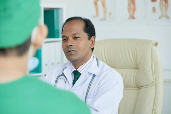 Indian doctor sitting at office and working with his colleague