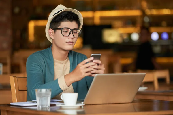Azjatycki Człowiek Kapelusz Okulary Przeglądania Telefonu Tabela Filiżanki Kawy Laptopa — Zdjęcie stockowe