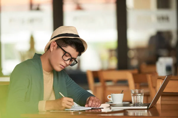 英俊的亚洲学生写在计划者在桌与膝上型计算机 — 图库照片