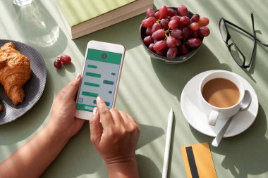 mutfak masası ve manifatura ile kahvaltı yaparken smartphone üzerinde oturan tanınmaz halde kadın
