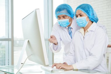 Tıbbi maske ve istatistik verileri bilgisayar monitör laboratuvar eğitim beyaz palto giyen doktorlar