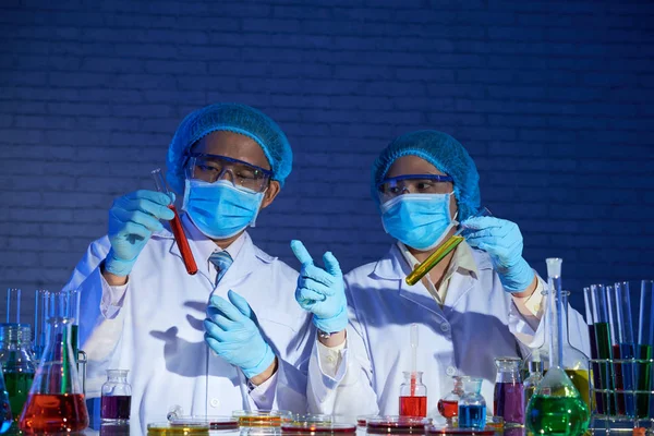 高度专业的医务人员在实验室用管子戴口罩和白大衣 — 图库照片