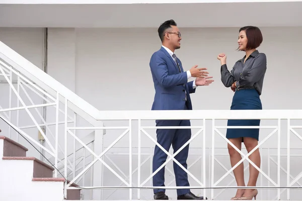 Улыбающиеся Азиатские Менеджеры Формальной Одежде Стоящие Лестнице Офисного Здания Разговаривающие — стоковое фото