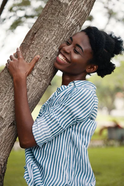 african-american woman hugging tree bark