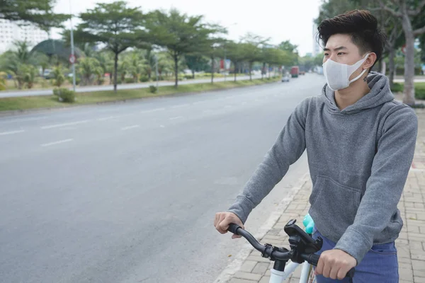 城市烟雾中的人脸面具骑自行车 — 图库照片