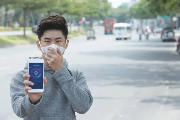年轻的亚洲男子在口罩显示红色警报通知智能手机 — 图库照片