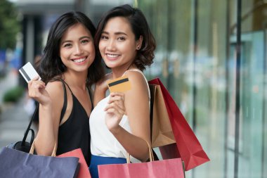 Kredi kartları ve alışveriş torbaları ile iki güzel Asyalı kadınlar