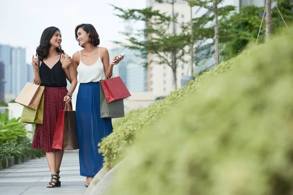 快乐的年轻越南妇女与纸袋聊天和步行在公园 — 图库照片