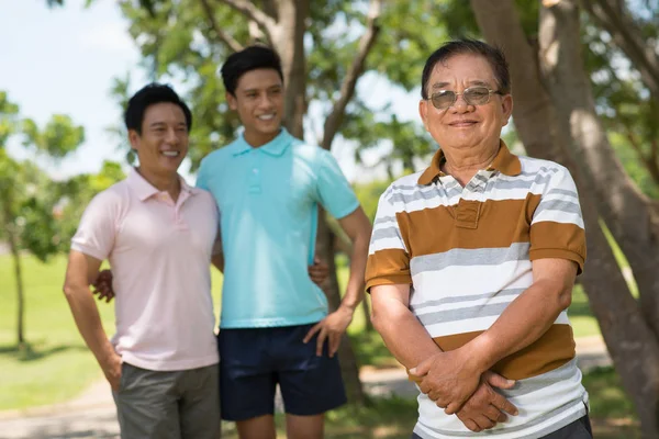 カメラのポーズの公園で幸せなアジア男性家族 — ストック写真