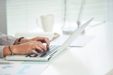 Laptop masada, kırpılmış görüntü ofiste çalışan iş kadın elinde 