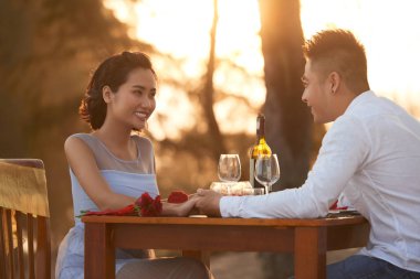 Seven Asya çift el ve birbirlerinin zevk tropikal kumsalda gün batımında romantik akşam yemeği yerken şirket holding