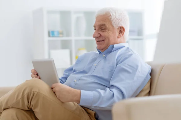 Lächelnder Älterer Herr Sitzt Bequemen Sessel Und Blättert Digitalen Tablet — Stockfoto