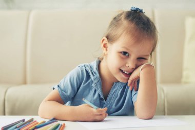 sevimli küçük kız evde çizim gülümseyen ve kameraya bakıyor 