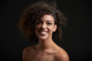 Gülümseyen çekici genç kadın kıvırcık afro saçlı Studio portresi 