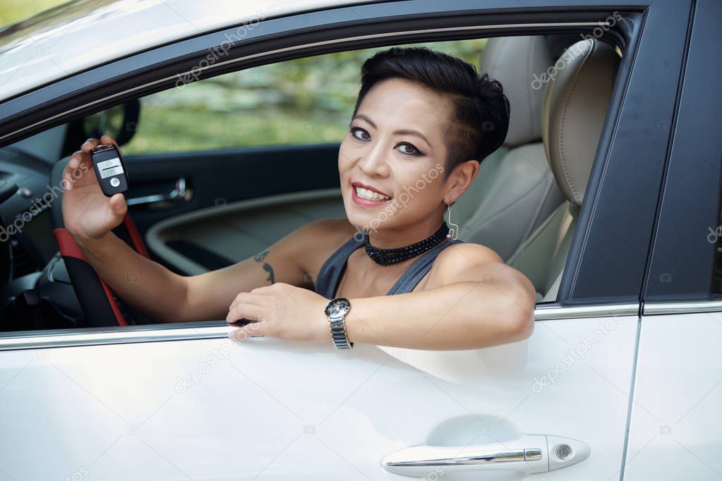 Happy stylish young woman showing keys of her new car