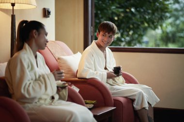 Genç çift spa işlemden sonra çay içme gülümseyen