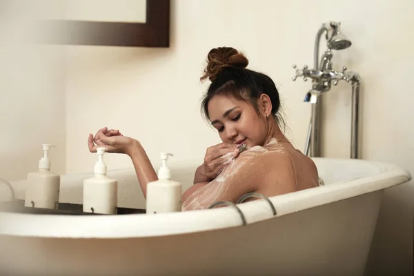 Asian woman washing her body while taking a bath