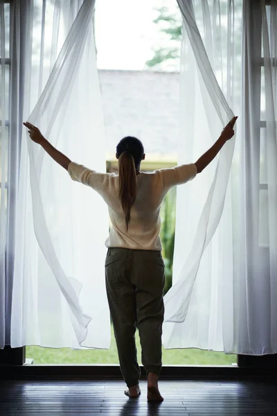 窓のそばに立って カーテンを開く若い女性 — ストック写真
