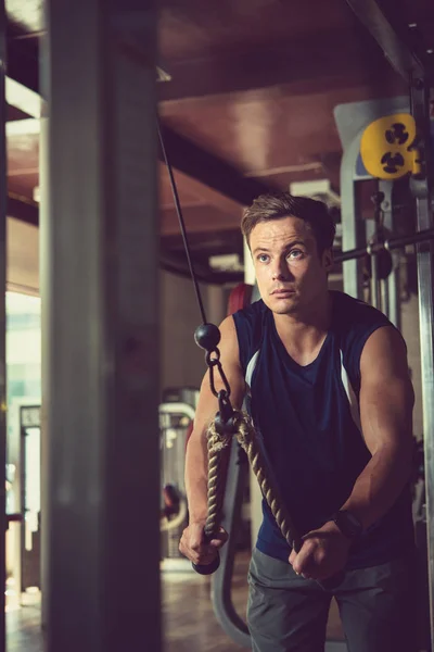 英俊运动的人做三头肌锻炼 同时在宽敞的健身房进行密集训练 — 图库照片
