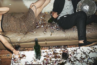 Tanınmayan adam ve kadın kanepe ellerini, alkollü içecekler ile renkli konfeti her yerde dağınık rahatlatıcı